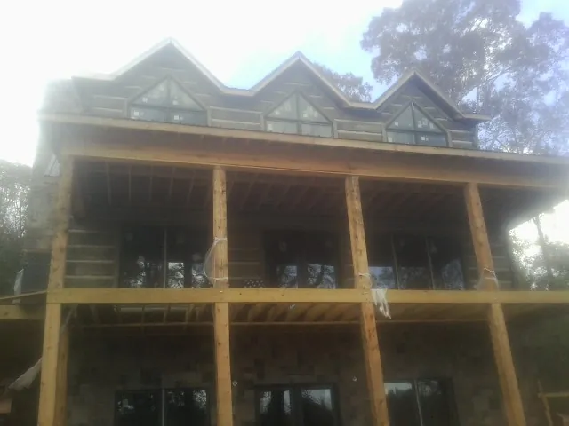 Dormers and porch framing on a large log home under construction — Roof Coating work by our crew in Rogersville